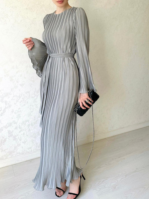 Full length picture of a woman wearing an elegant pleated bell sleeve mid-length grey dress with a mid-waist.