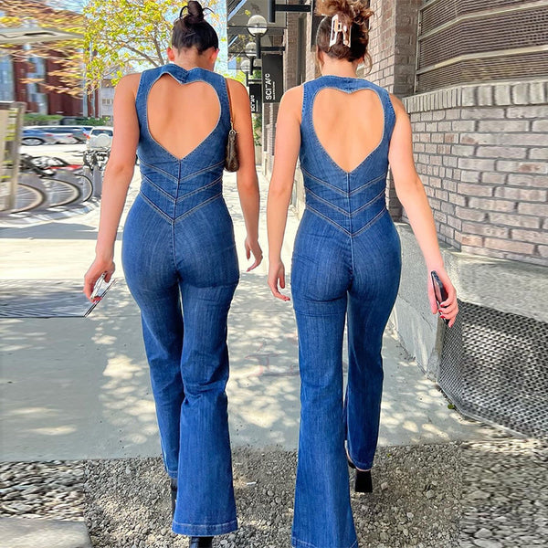 Two women walking on a sidewalk wearing backless denim jumpsuits with a heart-shape design at the top.