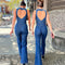 Two women walking on a sidewalk wearing backless denim jumpsuits with a heart-shape design at the top.