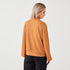 A lady wearing orange high neck sweatshirt, back click