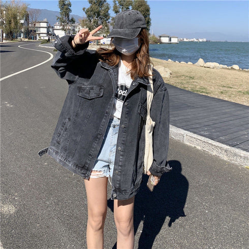 A lady posing for a picture wearing a loose denim jacket with a cap, mask, and sunglasses.