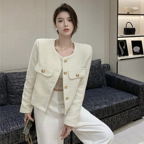 A woman posing for a camera wearing a beige long sleeve tweed jacket with round neckline and single-breasted button details.